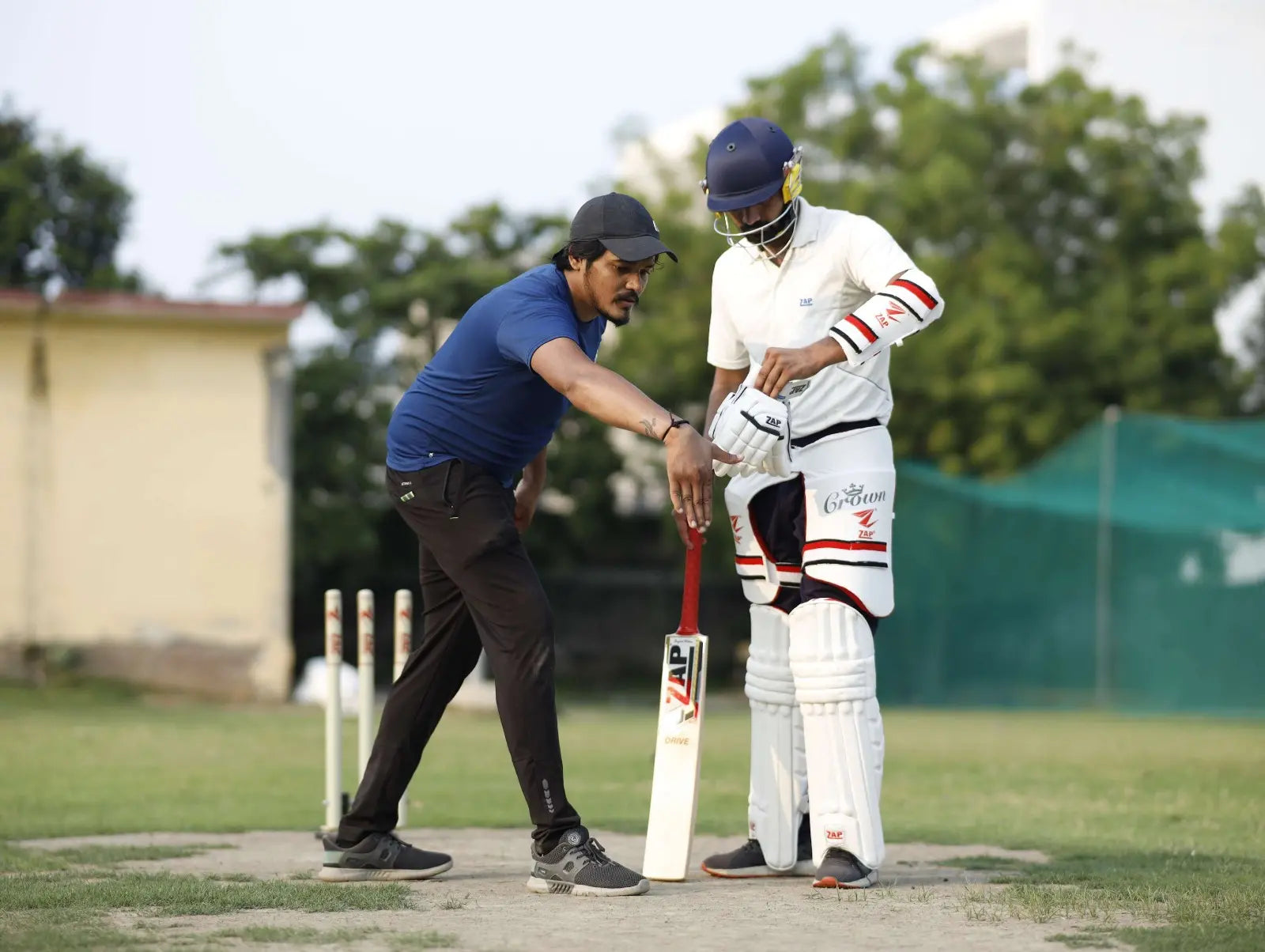 A Cricket Coach explaining a batsman the flaws in his batting style and how to improve upon it.