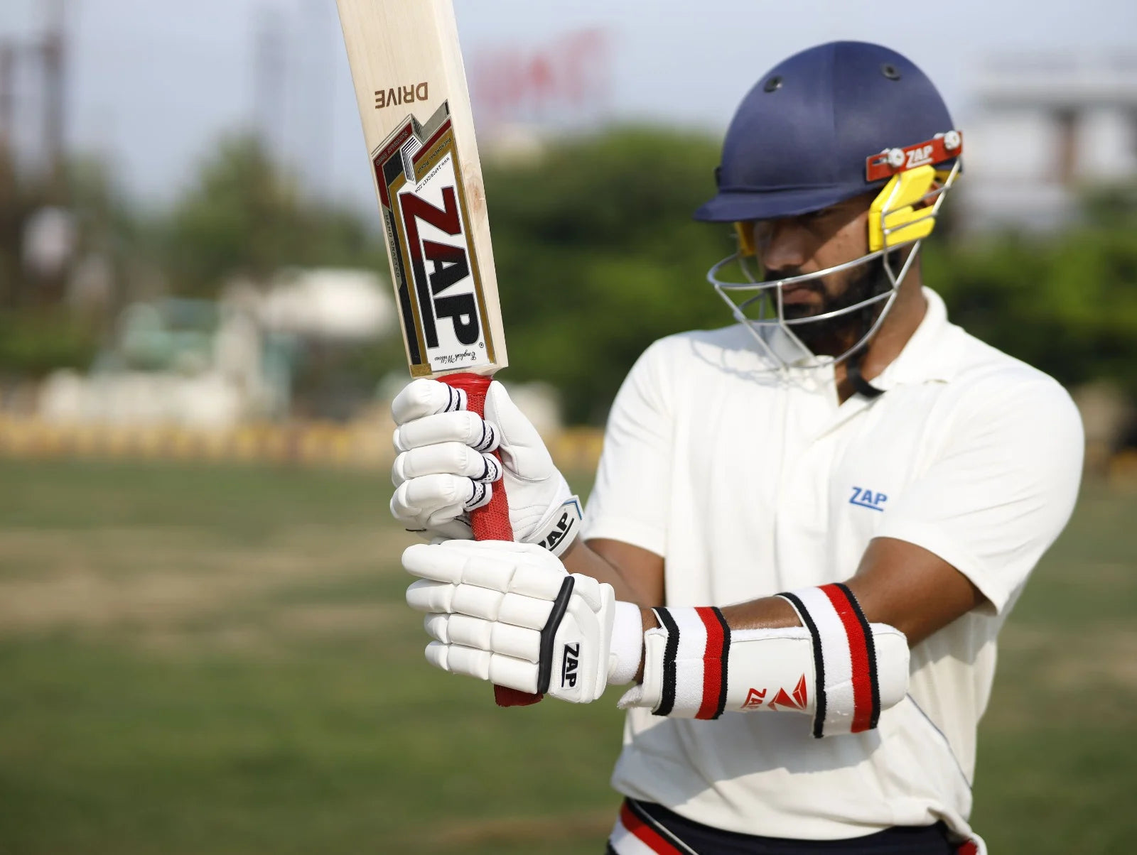 The batsman checks his grip holding a ZAP Cricket Bat before taking his batting stance